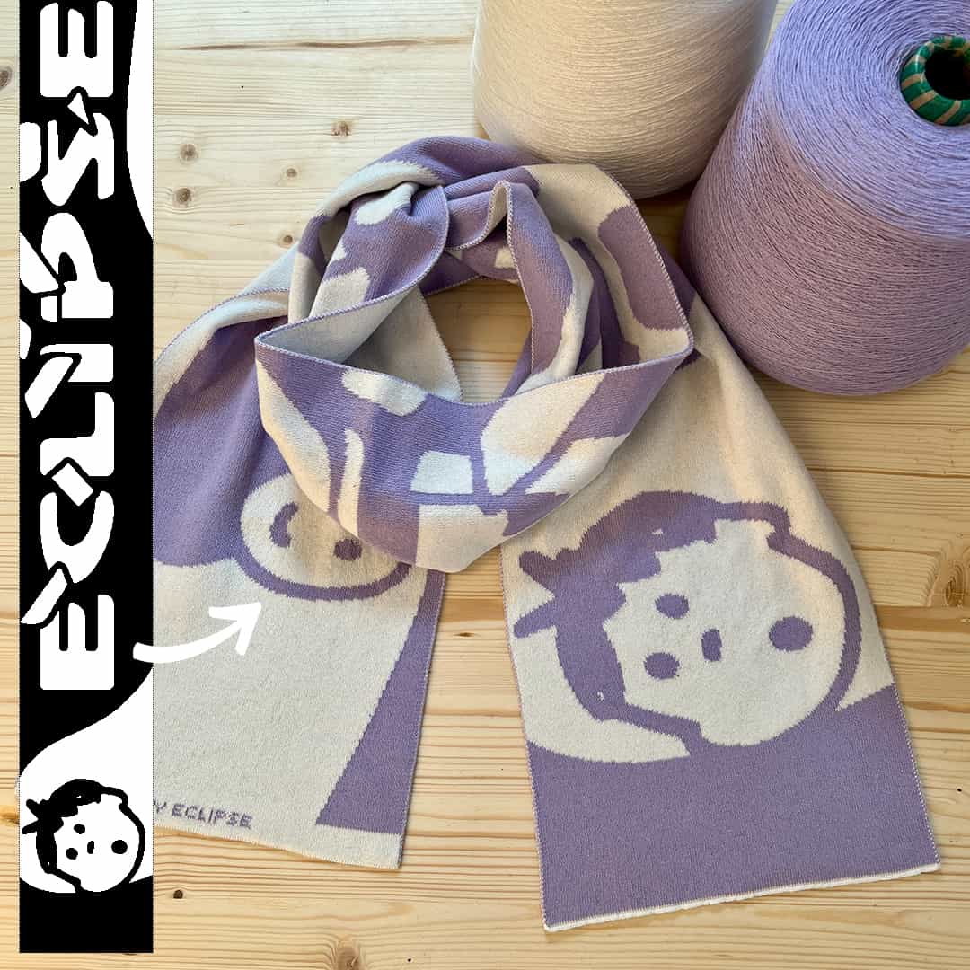 Gebreide kindersjaal met zacht illustratief ontwerp naast breigarens