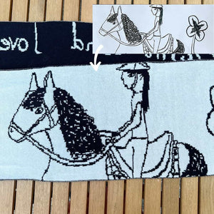 Een zwart-witte kindersjaal met een tekening van een meisje dat op een paard zit.